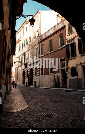 Es gibt eine schmale Straße mit einem Mannlochdeckel, der sich in der Mitte der Straße für Fußgänger und Autos befindet Stockfoto