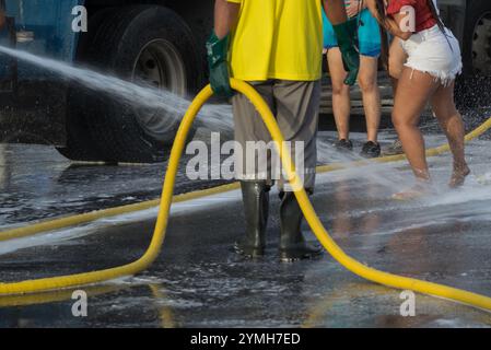 Mann, der einer Frau die Füße nass macht, mitten auf der Straße, heißer, sonniger Tag. Dreckige Füße, Reinigung. Salvador, Brasilien. Stockfoto