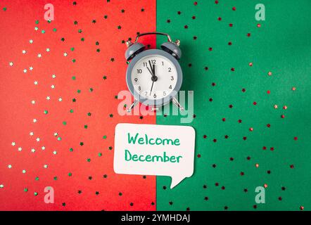Die Uhr ist auf grünem Hintergrund mit einem weißen Schild, das auf „Welcome December“ steht. Die Uhr befindet sich auf der linken Seite des Schildes und der Hintergrund ist rot Stockfoto