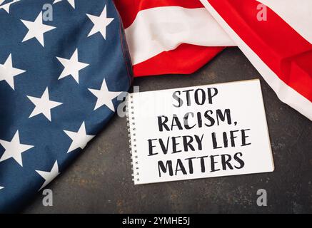 Weißes Stück Papier mit den Worten Stop Rassismus, Every Life Matters darauf geschrieben. Sie wird auf einer rot-weißen amerikanischen Flagge platziert Stockfoto