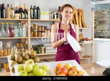 Die Verkäuferin für Erwachsene bietet Milch im Lebensmittelgeschäft an Stockfoto