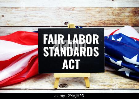 Textgitter des Fair Labor Standards Act mit US-Flagge auf hölzernem Hintergrund Stockfoto