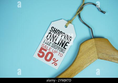 Shopping Online Sale bis zu 50 % zum Preis mit hölzernem Kleiderbügel von oben auf blauem Hintergrund, Business- und Promotion-Unterkonstruktion Stockfoto