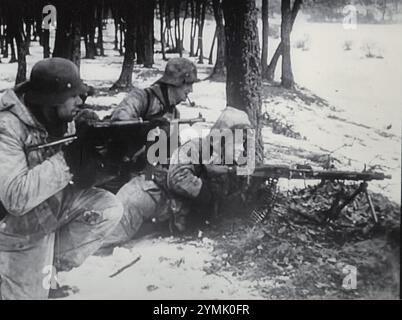 Weltkrieg zwei Schwarzweißfotos Deutsche Truppen in Winter Camo ziehen mit einem MG und anderen Waffen am Waldrand in Ungarn 1945 in eine Verteidigungsposition Stockfoto