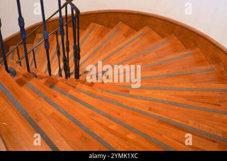 Eine elegante und wunderschön gefertigte, geschwungene Holztreppe mit stilvollem Metallgeländer Stockfoto