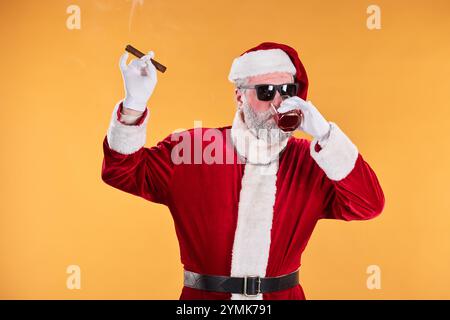 Der Weihnachtsmann trägt einen traditionellen roten Anzug und genießt Zigarren und Drinks, während er eine Sonnenbrille trägt, was ein kühles und entspanntes Auftreten ausstrahlt. Hintergrund ist eine einfarbige Farbe, die eine festliche Atmosphäre verleiht Stockfoto