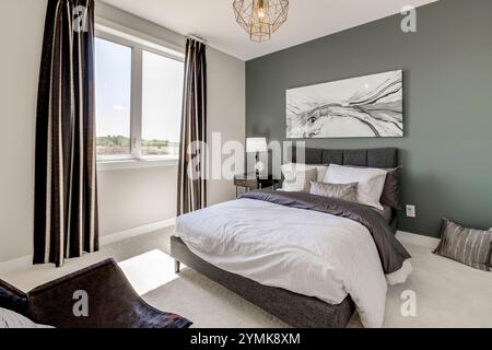 Ein Schlafzimmer mit einem weißen Bett und einem Schwarzweißbild an der Wand. Der Raum ist hell und luftig, mit einem Fenster, das natürliches Licht einlässt. Das Bett ist Stockfoto