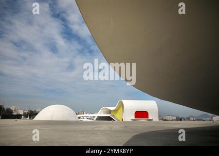 Das Memorial Roberto Silveira (links), das 2003 eröffnet wurde, und das Oscar Niemeyer Popular Theater (rechts), das 2007 eröffnet wurde, sind abgebildet. Sie sind Teil des „Niemeyer Way“, einer Serie von sieben Gebäuden, die Oscar Niemeyer in Niterói, Brasilien, entwarf. Oscar Niemeyer ist einer der berühmtesten Architekten Brasiliens. Er gehört der International Style Movement an. Er ist bekannt für den Bau der brasilianischen Hauptstadt Brasilia mit dem Stadtplaner Lúcio Costa, der 1960 eröffnet wurde. Niteroi, gegenüber der Guanabara-Bucht von Rio de Janeiro, ist nach Brasilia die zweite Stadt der Welt mit den meisten Niemeyer-Gebäuden Stockfoto