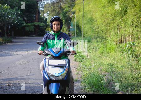 Online-Taxifahrer mit grüner Jacke und Helm, Motorrad unterwegs, um Kunden abzuholen. Transportanwendungskonzept. Stockfoto