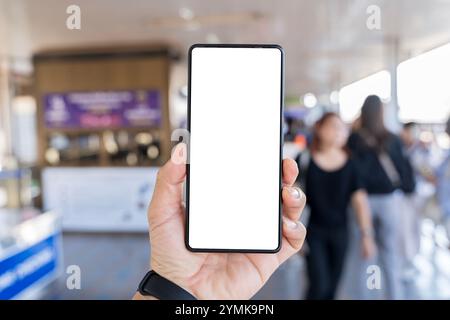 Die Hand des Mannes hält Handy mit weißem, leerem Bildschirm vor dem unscharfen U-Bahn-Zug, der auf den Bahnsteig einsteigt, mit Zug im Hintergrund. Modell von Stockfoto