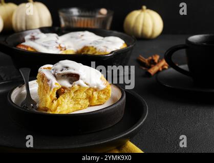 Kürbisbrötchen Hefebrot oder zimt mit Gewürzen auf Teller und Tasse Tee auf schwarzem Hintergrund. Thanksgiving oder Frühstück Essen Konzept. Herbstkonzept Stockfoto