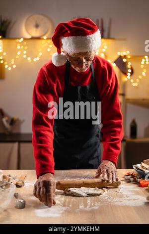 Ein älterer Mann, der an weihnachten Teig für Lebkuchen zubereitete. Kochen von Gebäck für Freunde in der Weihnachtszeit Stockfoto