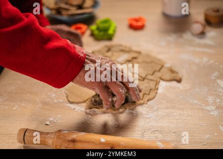 Weihnachts- und Neujahrstraditionen. Weihnachtsbäckerei in der Küche. Man macht Lebkuchen, schneidet Kekse aus Lebkuchen Teig. Kochen Stockfoto