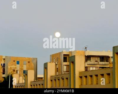 Kairo, Ägypten, 15. November 2024: Ägyptisches Gizeh in der Stadt Scheich Zayed mit Gebäuden und einem Vollmond bei Sonnenuntergang Stockfoto