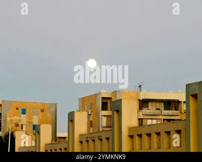 Kairo, Ägypten, 15. November 2024: Ägyptisches Gizeh in der Stadt Scheich Zayed mit Gebäuden und einem Vollmond bei Sonnenuntergang Stockfoto