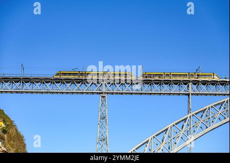 Porto, Portugal - 25. Juli 2024: Brücke Luis I. Eine Straßenbahn mit öffentlichen Verkehrsmitteln, die auf dem alten Metallbau vor blauem Himmel fährt. Stockfoto