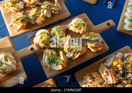 Auf Holzbrettern werden verschiedene Hühnchengerichte präsentiert, darunter einige mit Grünzeug. Die Präsentation ist farbenfroh und appetitlich, mit einer Mischung Stockfoto