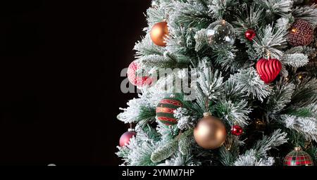 Weihnachtsbaum mit traditioneller Weihnachtsdekoration, beleuchtet von Weihnachtslichtern, die mit einem Spiel von Schatten und Lichtern aufleuchten Stockfoto