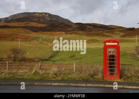 Eine Frau benutzt eine rote Telefonzelle auf der Isle of Skye, Schottland, Großbritannien. Diese Art von Stand namens K6 wurde 1935 eingeführt, zuerst in London, dann im ganzen Vereinigten Königreich. Stockfoto