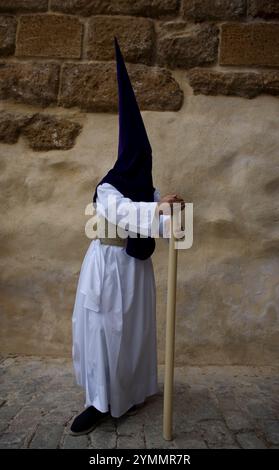 Ein Pönitent hält eine Kerze während einer Karwoche-Prozession im Dorf Carmona, Provinz Sevilla, Andalusien, Spanien. Stockfoto