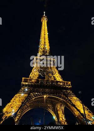 Paris, Frankreich - 19. Juni 2024: Nächtlicher Blick auf den Eiffelturm, wunderschön beleuchtet mit den Olympischen Ringen. Dieses ikonische Pariser Wahrzeichen fängt ein Stockfoto