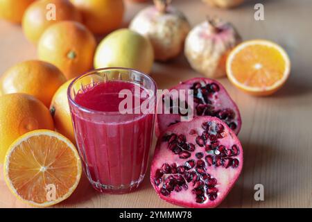 Frischer Orangen- und Granatapfelsaft in einem Glas und schneidet Früchte bereit zum Auspressen Stockfoto