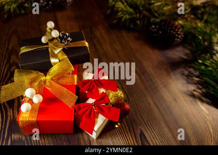 Weihnachtsbanner mit vielen Geschenkboxen, die mit roten und goldenen Bändern und Weihnachtsbaumdekorationen auf hölzernem Hintergrund gebunden sind. Frohe Weihnachten Stockfoto