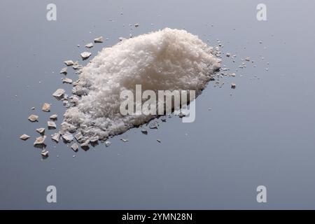 Flocken von knusprigem maldon-Kristallen-Salz auf hellblauer reflektierender Oberfläche Stockfoto