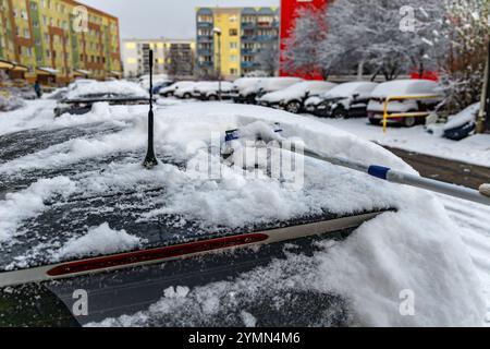 Eine Frau schaufelt Schnee aus dem Auto, entfernt Eis von der Karosserie, Winterangriff, bereitet das Auto auf die Route vor Stockfoto