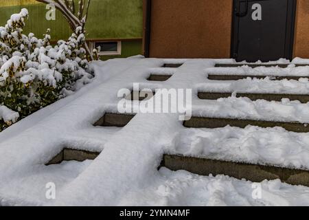 Erster Schneefall, schneebedeckte Treppen und Rollstuhlrampe, die zum Haus führt, Vorsicht vor rutschigen Treppen Stockfoto