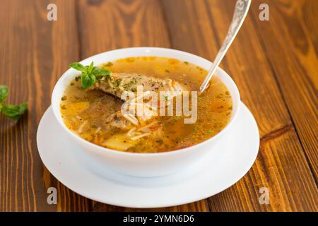 Heiß gekochte Hühnchen- und Nudelsuppe auf einem Teller auf einem Holztisch. Stockfoto
