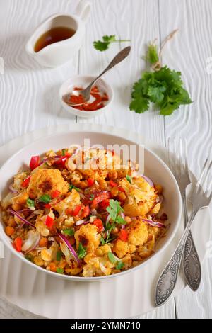 Gebratener Blumenkohl-Quinoa-Salat mit Walnüssen, rotem Pfeffer, Zwiebeln und Koriander in weißer Schüssel auf weißem Holztisch mit Gabeln, vertikale Ansicht f Stockfoto