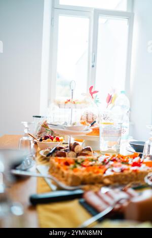 Speisesaal mit einem wunderschön gestalteten Brunch-Tisch mit einer Auswahl an frischem Gebäck, Obst und Fingerfood, perfekt für ein warmes Familientreffen Stockfoto