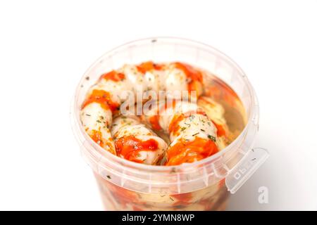 Behälter mit Surimi in Form von Garnelensoße und weißem Hintergrund. Das Essen ist im Behälter und ist eine Art Fisch und Meeresfrüchte. Stockfoto