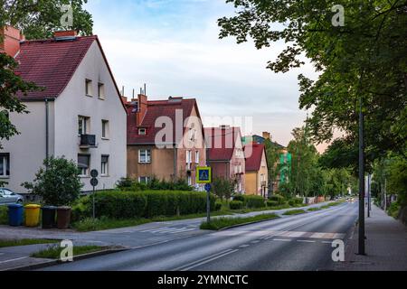 Wunderschöne dreistöckige Häuser mit roten Dächern, umgeben von Grün, stehen an der Straße. Stadtlandschaft. Stockfoto