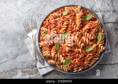 Italienische Fusilloni-Pasta oder große Fusilli mit Bolognese-Sauce in Nahaufnahme auf einem Teller auf dem Tisch. Horizontale Draufsicht von oben Stockfoto