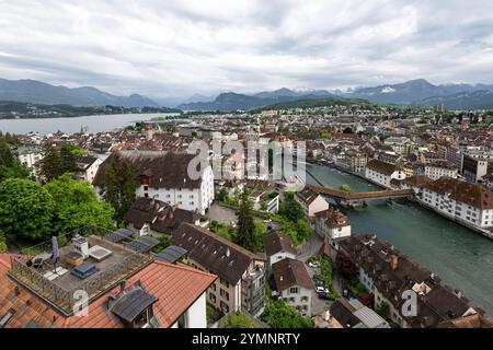 Alte und moderne Gebäude, die sich um einen Zusammenfluss von See und Fluss mit hohen Bergen im Hintergrund schmiegen Stockfoto