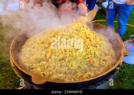 Es ist ein traditionelles türkisches Pilaw, das in einem großen gusseisernen Kessel gekocht wird Stockfoto