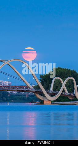 Die Menschen beobachten, wie der Buck Moon von einer Fußgängerbrücke aus in Kiew, Ukraine, über die Stadt aufsteigt. Stockfoto