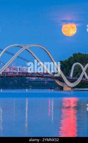 Die Menschen beobachten, wie der Buck Moon von einer Fußgängerbrücke aus in Kiew, Ukraine, über die Stadt aufsteigt. Stockfoto