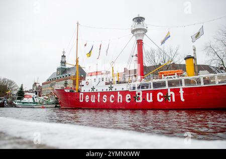 Emden, Deutschland. November 2024. Das historische Leuchtschiff „Amrumbank“ und der Rettungskreuzer „Georg Breusing“ liegen bei winterlichem Wetter im Ratsdelft in der Innenstadt, während Schnee die Kaimauer bedeckt. Im Hintergrund ist das historische Rathaus von Emden zu sehen. Quelle: Hauke-Christian Dittrich/dpa/Alamy Live News Stockfoto
