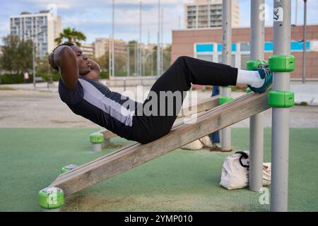 Junger schwarzer Mann, der Calisthenics-Sit-UPS im Freien macht Stockfoto