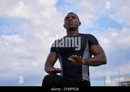 Schwarzer Mann, der draußen unter bewölktem Himmel Calisthenics macht Stockfoto