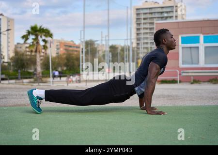 Junger schwarzer Mann, der draußen Calisthenics Pseudo-Planche-Liegestütze macht Stockfoto