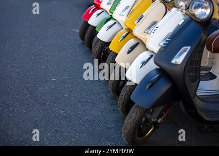 Neue Retro-Motorroller parken nebeneinander auf einer Straße. Vintage-Motorräder in leuchtenden Farben in Folge Stockfoto