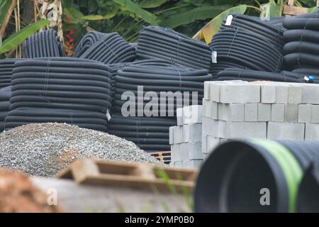Ein großer Stapel schwarzer Rohre und Ziegelsteine sind in einem Stapel gestapelt. Die Ziegel haben verschiedene Größen und werden zufällig gestapelt. Die Rohre sind als Stockfoto