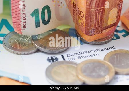 Berlin, Deutschland. November 2024. Münzen und Banknoten befinden sich auf einem Brief des Bundessteueramtes. Das Bundeszentrale Steueramt (BZSt) ist Teil des Bundesministeriums für Finanzen (BMF). Es ist eine Bundesoberbehörde, die dem BMF unterstellt ist und verschiedene Aufgaben im Bereich der Besteuerung wahrnimmt, wie die Verwaltung der Umsatzsteuer-Identifikationsnummern, die Abwicklung des automatisierten Informationsaustauschs und die Bearbeitung von Steuererstattungen. Quelle: Fernando Gutierrez-Juarez/dpa/Alamy Live News Stockfoto