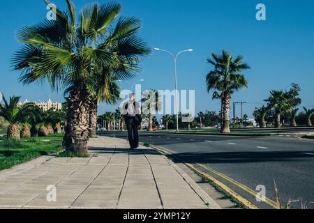 Ein Mann läuft auf einer Straße mit Palmen an der Seite Stockfoto