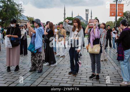 Japanische Touristen machen Fotos im Sultanahmet Park mit der Blauen Moschee (Sultanahmet Camii) im Hintergrund, Istanbul, Türkei Stockfoto