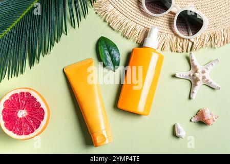 Sommerurlaub, UV-Schutzkonzept. Orangefarbene Sonnenschutzmittel, Sonnenbrille, Strohhut, Seesterne und Palmblätter auf grünem Hintergrund. SPF Sonnenschutzmittel c Stockfoto